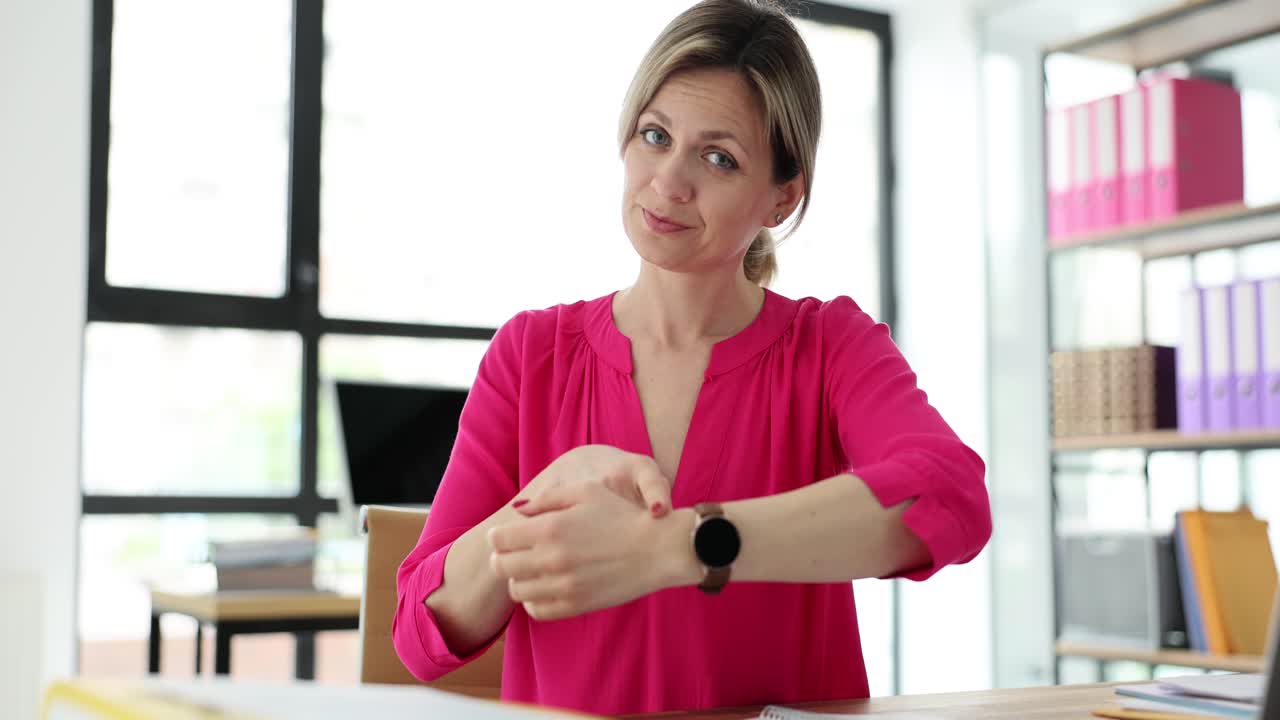 Manager donna mostra l'orologio accennando all'ora, seduta al tavolo