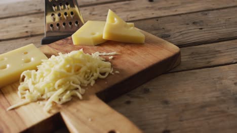 Video-Von-Gelbem-Käse-Und-Geriebenem-Käse-Auf-Holzbrett-Mit-Käsereibe-Auf-Rustikalem-Tisch