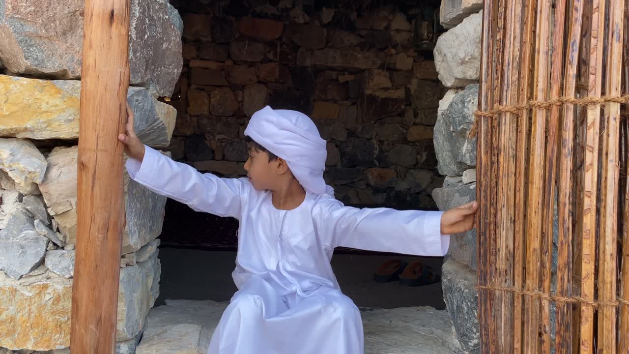 niño árabe en una casa tradicional árabe hecha de piedra