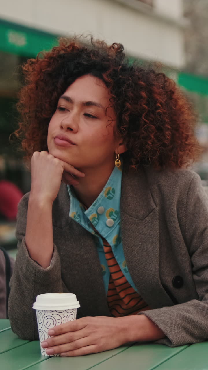 Thoughtful Woman Sits at Outdoor Cafe