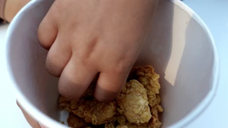 hand grabbing fried chicken from a paper cup