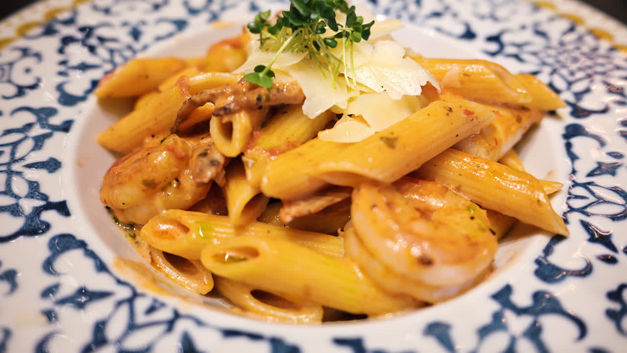 Penne seafood pasta with shrimps and parmesan cheese in a beautiful ceramic plate