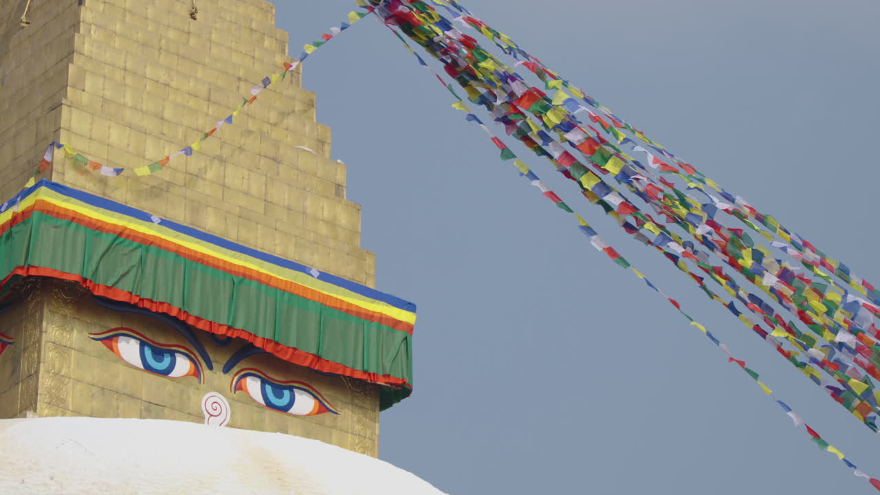 Close-up of Boudhanath Stupa, Kathmandu, Nepal. Buddhist prayer flags flow gently in the sunny sky as Buddha eyes gaze peacefully, radiating spiritual vibes and sacred cultural heritage