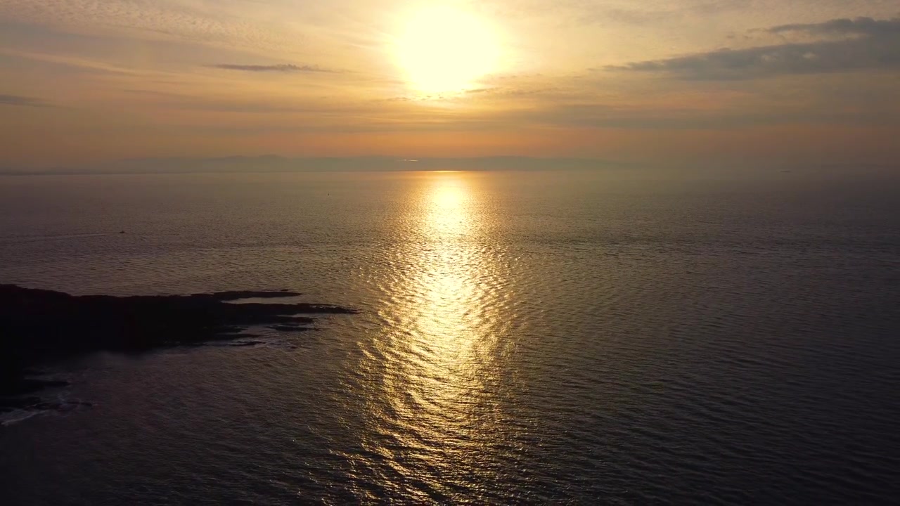 Beautiful Aerial with Sun Reflecting on Calm Ocean at Sunrise. Ideal for meditation videos or peaceful nature backgrounds. 4K.