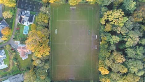 alejar, vista aérea superior en el campo de fútbol en medio del parque de otoño junto a casas de campo con piscina y cancha de tenis