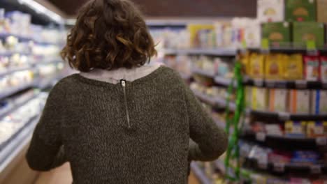 vista rara de una mujer feliz y emocionada en suéter fue de compras con un carrito de tranvía - caminar por una fila y saltar felizmente. cámara lenta