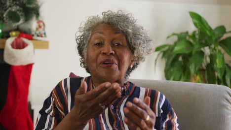 happy african american senior woman gesturing, having video call at christmas time