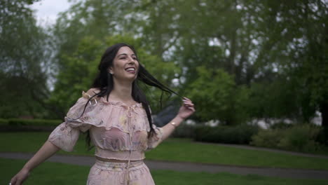 attractive and carefree brunette tourist spinning around with a floral dress at the park in london, happy and cheerful