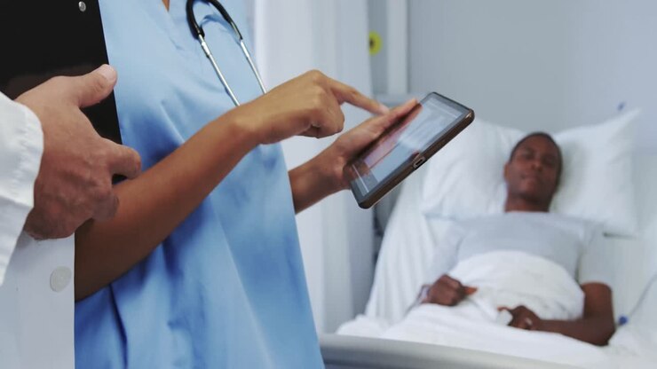 Close-up of multi-ethnic doctors discussing x-ray report on digital tablet in ward at hospital
