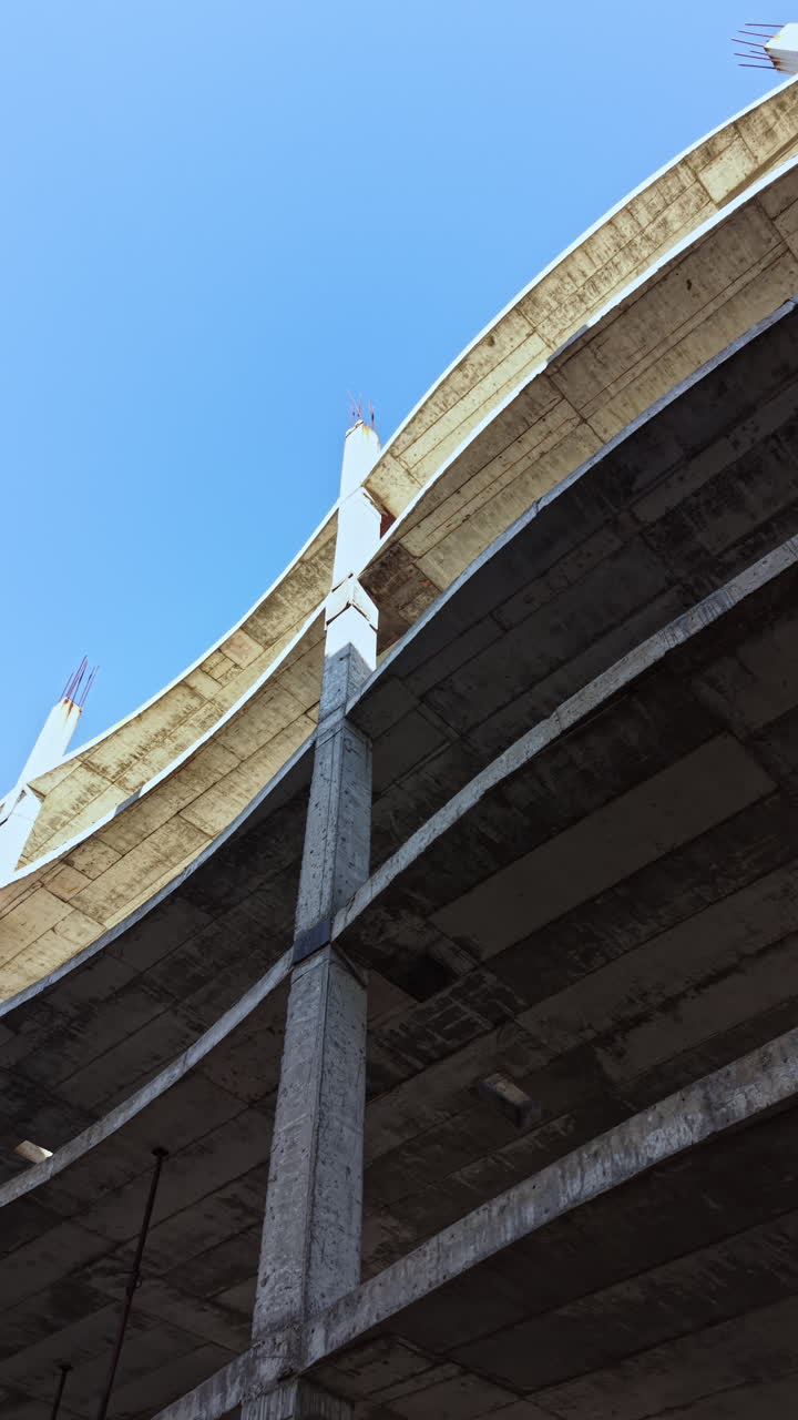 La struttura in cemento cattura l'essenza dell'architettura urbana con le sue linee audaci e le curve ampie su un cielo azzurro.