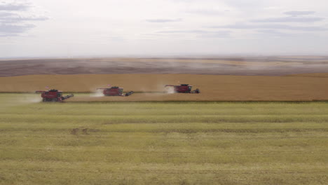 industrial farming in america with three large combine harvester in field