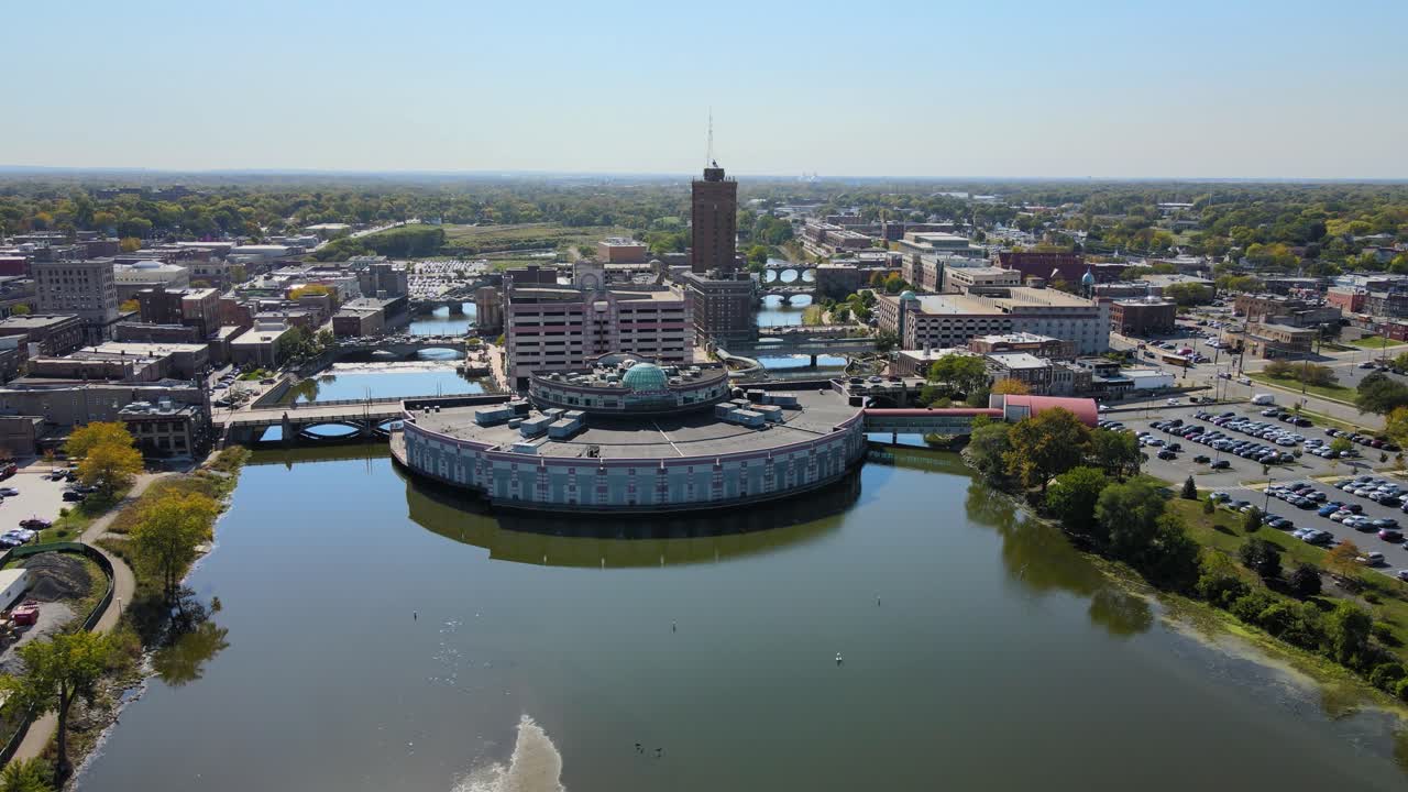 Drone footage capturing downtown Aurora, IL, a Chicago suburb in the Chicagoland area, near the river, buildings, and the Metra train line. Orbit Right Day S