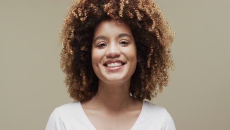 Happy-biracial-woman-with-dark-hair-on-beige-background-with-copy-space,-slow-motion