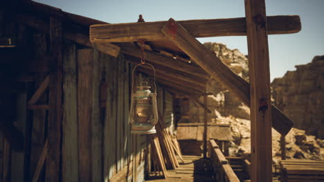 a rusty lantern hangs from a wooden post outside an old cabin in the desert