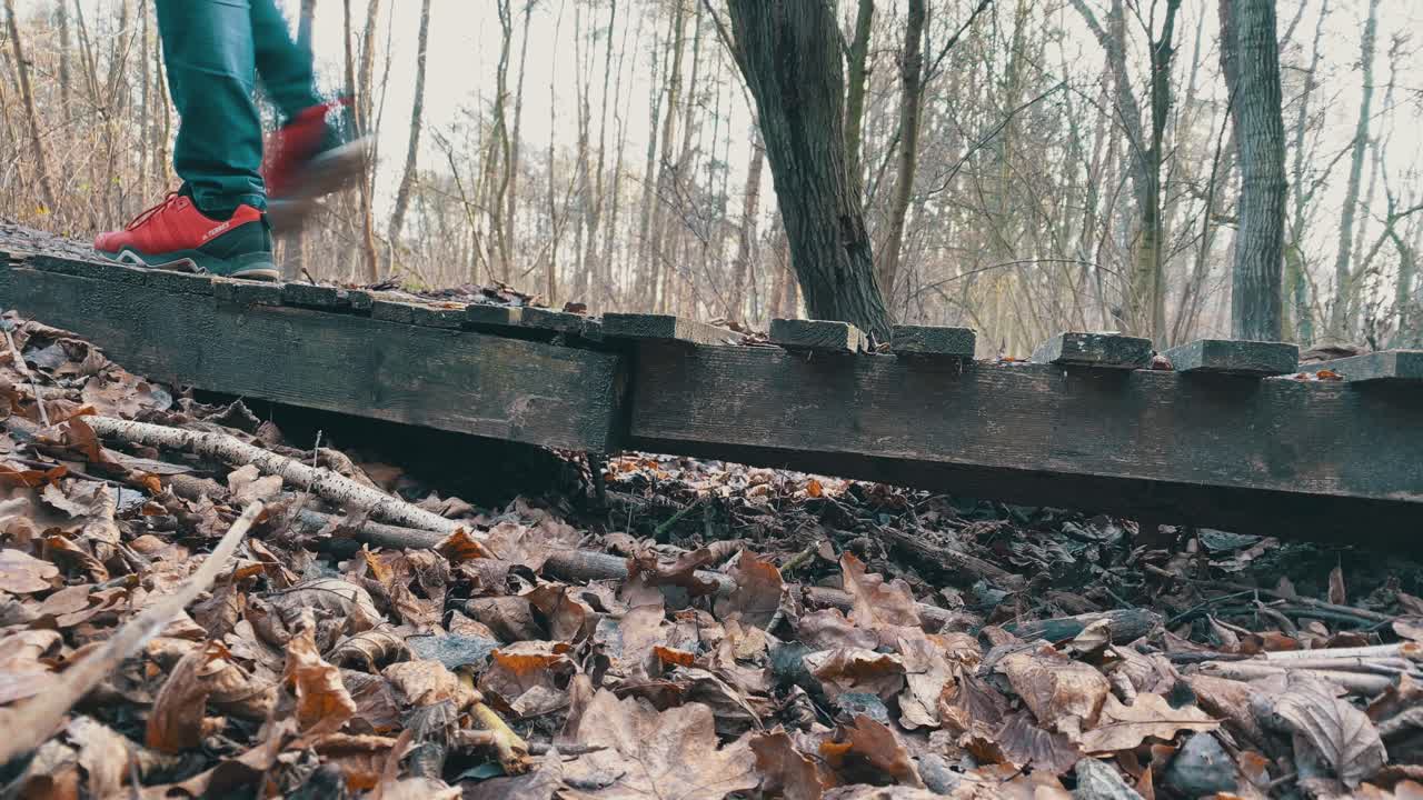 한 사람 이 느린 속도로 은 나무 다리 를 가로질러 고 있다