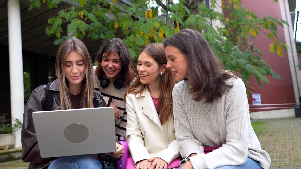 Studentesse felici che usano il laptop insieme nel campus universitario