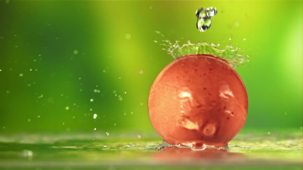 Gocce d'acqua al rallentatore che schizzano su un acino d'uva rosso fresco.