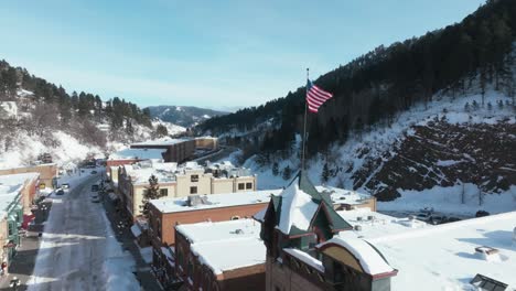 American-Flag-waving-over-Deadwood,-South-Dakota-in-winter