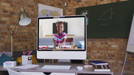 african american girl having online school lesson on screen of computer on desk