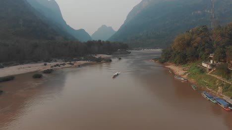 Small-local-boat-cruising-on-Nam-ou-river-at-Muang-ngoy-Laos,-aerial