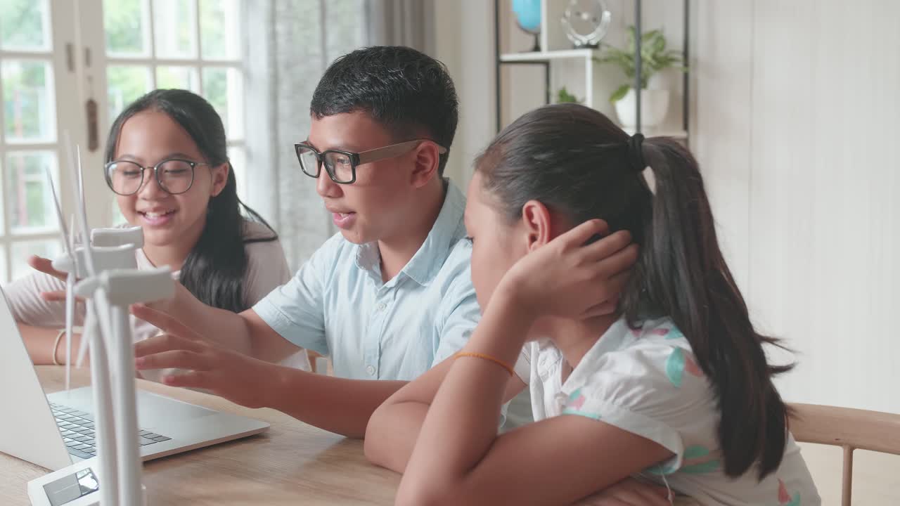 Class Of Smart Young Asian Children Work As A Team Using Laptop Computers To Program Wind Turbines