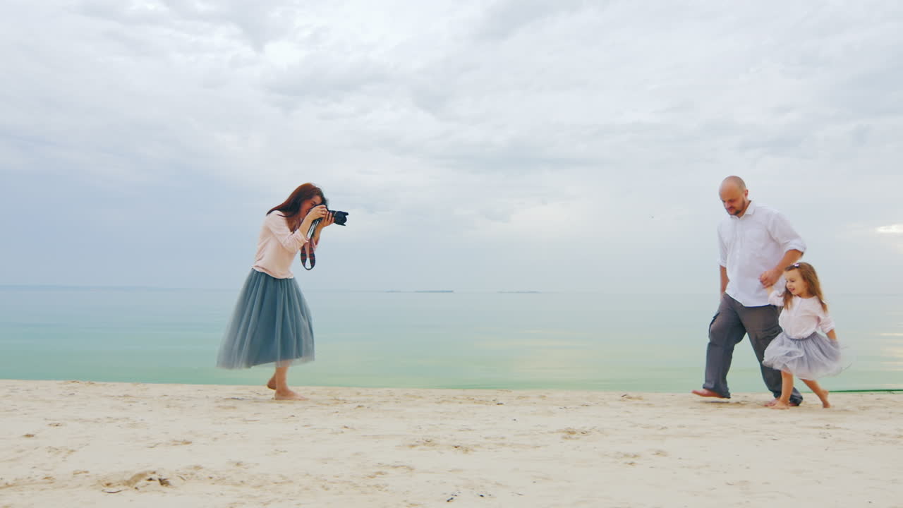 가족 사진 촬영 엄마는 해변에서 아빠와 딸 사진을 찍습니다