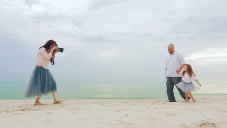 family photo shoot mom takes pictures dad and daughter on the beach