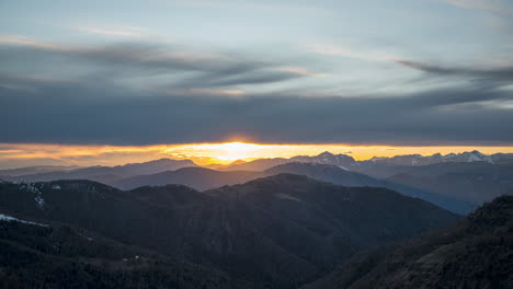 Sunset-over-mountainous-landscape-with-dramatic-clouds-and-soft-light,-scenic-view