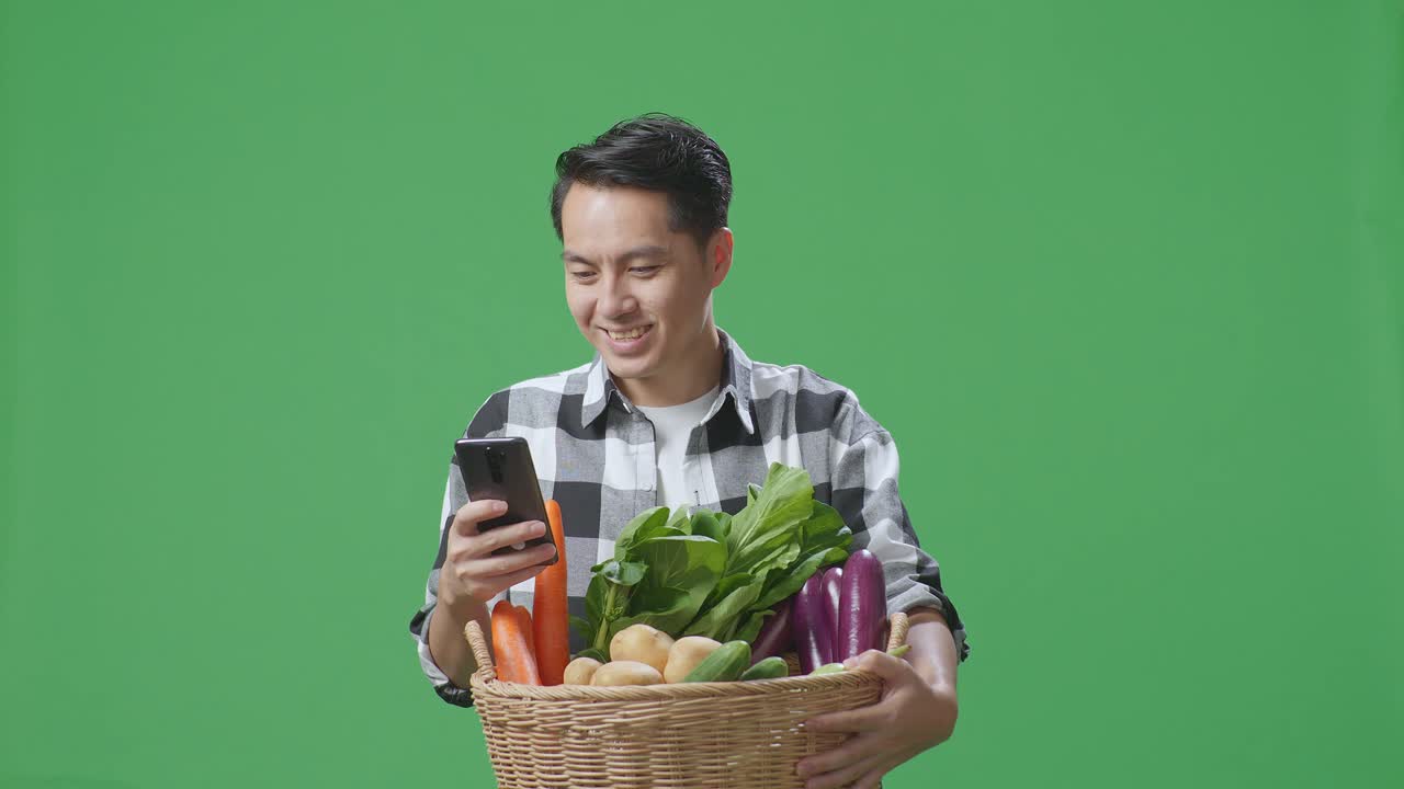 채소 바구니를 들고 스마트폰을 사용하는 남자