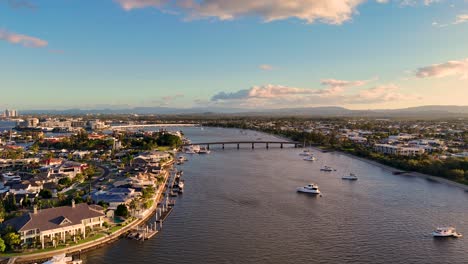 Drone captures serene Gold Coast waterways with luxury estates and boats under warm sunset lighting, showcasing a tranquil coastal atmosphere