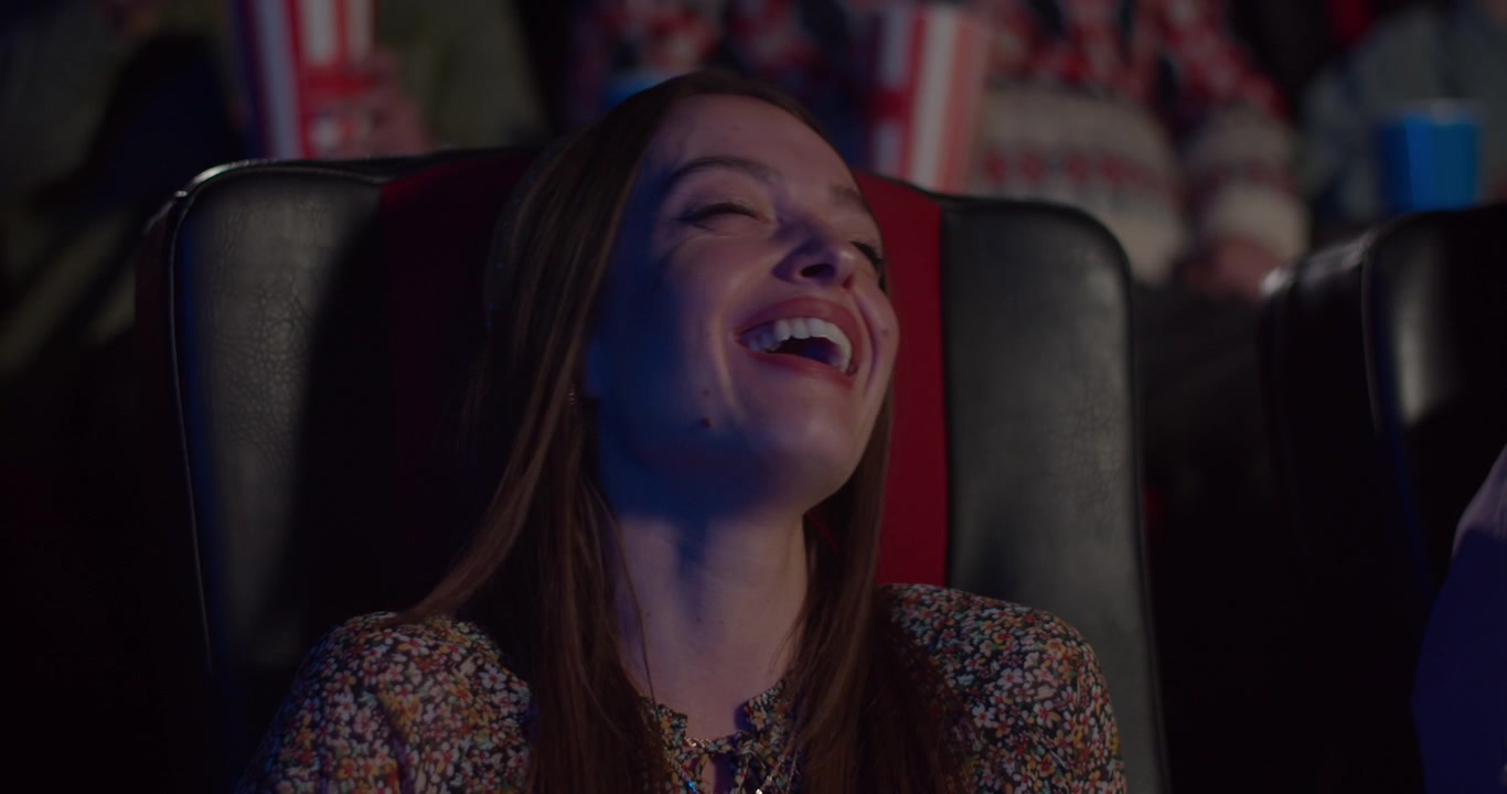 Young Woman Laughing While Watching a Movie in a Cinema