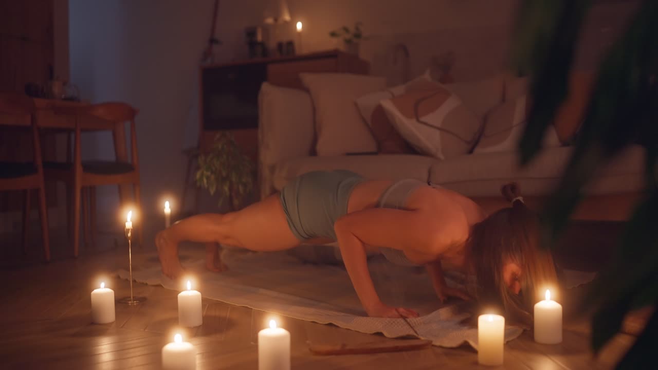 Donna che pratica yoga a casa di notte con le candele
