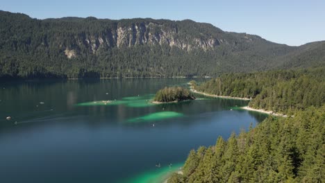 Hermoso-Lago-Rodeado-De-árboles-Y-El-Agua-Parece-Tener-Tonos-De-Verde-Y-Azul.-Se-Pueden-Ver-Numerosos-Botes,-Personas-En-Botes-Disfrutando-De-La-Vista-Panorámica,-Una-Atmósfera-Surrealista-Y-Peculiar,-Cielo-Despejado.