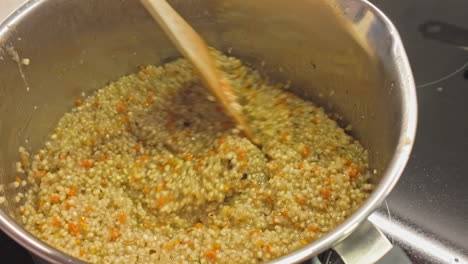 un primer plano de couscous preparándose con una cuchara de madera