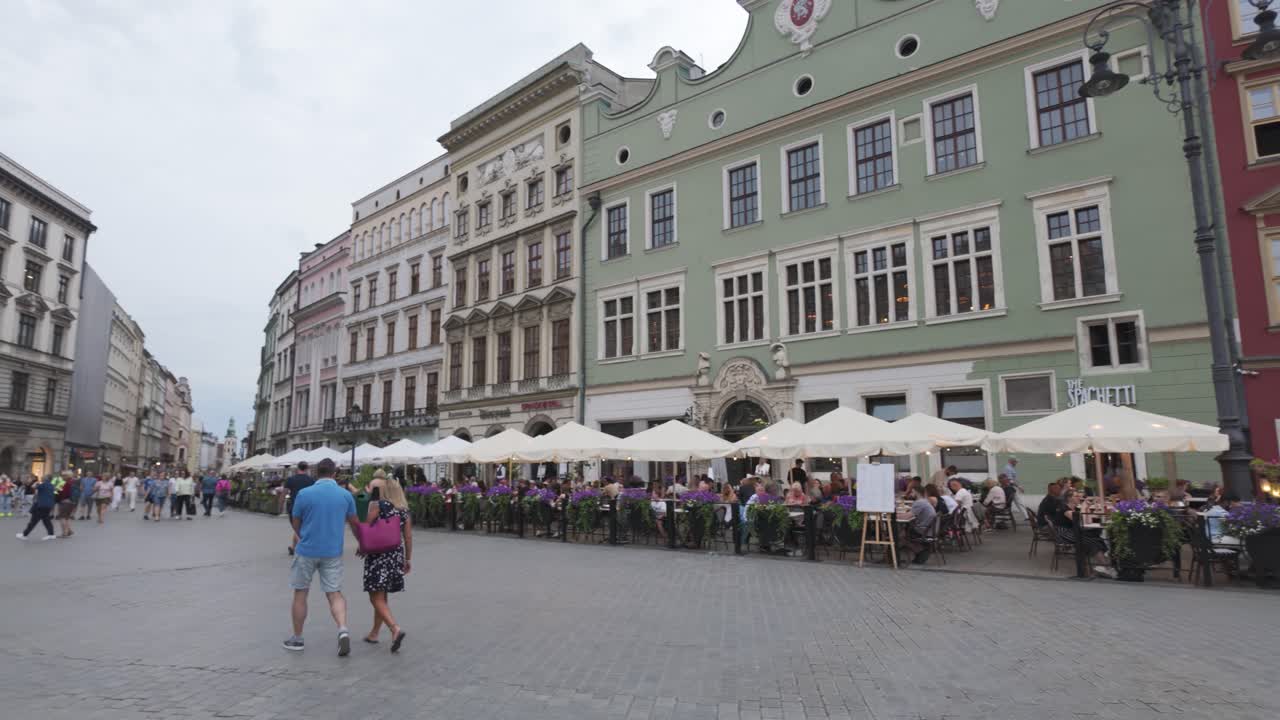 Krakow’s Main Square on a cloudy day with tourists walking around and historic architecture in view