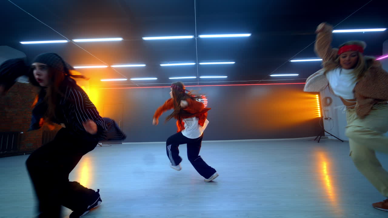 Hip hop dance style performed in modern studio. Girls trio moving energetically in the spacious room.