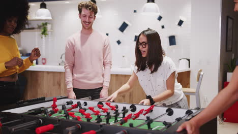 compañeros de negocios creativos del milenio toman un descanso jugando al fútbol de mesa en el trabajo, de cerca