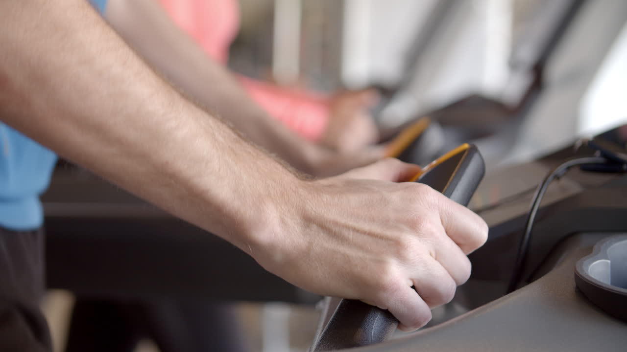 hombre presionando botones en una máquina de correr en el gimnasio, detalle