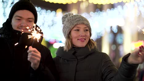 couple celebrating winter night with sparkler