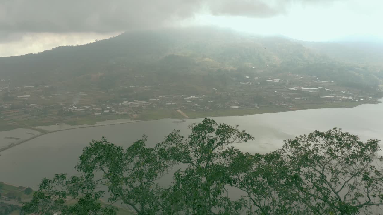 Aerial Video; A slow rise over a tree to reveal an idyllic lakeside city.