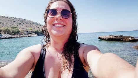 happy woman vlogging beach day with yachts at vouliagmeni lake