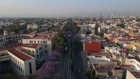 Aerial-backwards-street-view-typical-bus-drive-in-street-traffic-on-multi-lane-road-surrounded-by-houses-in-city-suburbs-neighborhood