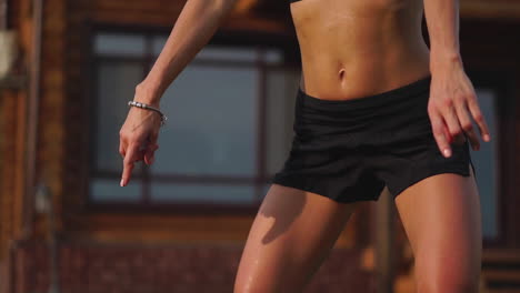 beautiful brunette on the background of a large mansion, engaged in the gym and perform squats, exercise in the open air