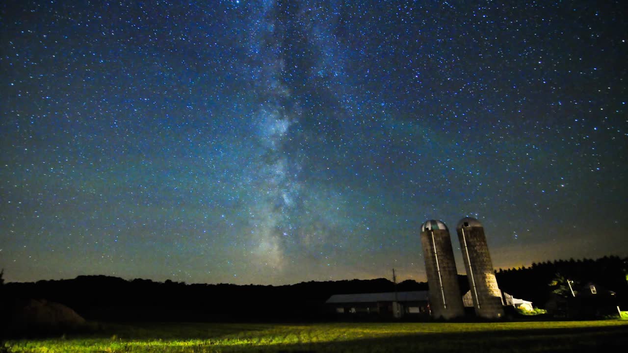 농장 사일로와 들판 위로 미끄러지는 은하수 시간 경과