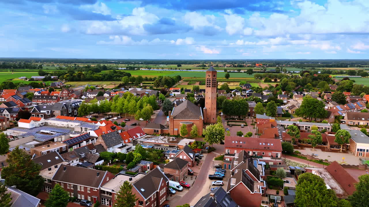 Drone view of Dutch town with church tower and surrounding houses. Aerial drone view of a Dutch town with a prominent church tower and surrounding houses and fields