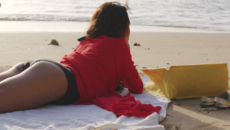 해변 해안 모래에서 쉬고 있는 예쁜 라틴계 소녀는 세련된 표정을 다시 찾습니다.