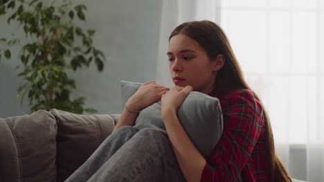 Pensive-lady-cries-hugging-pillow-on-sofa-in-living-room