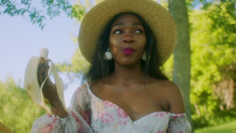 beautiful black woman eating banana in park close up