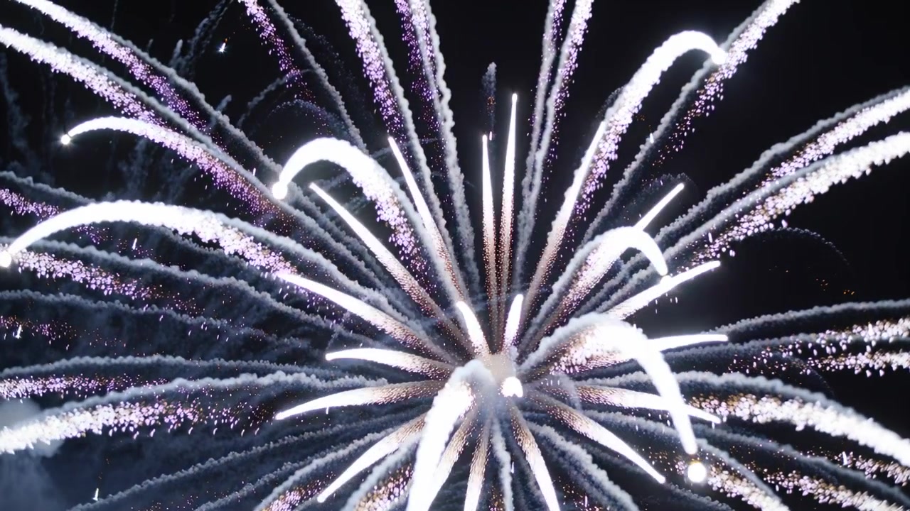 Exploding firework shell sending bright core, white-purple sparks and smoke into night sky for show