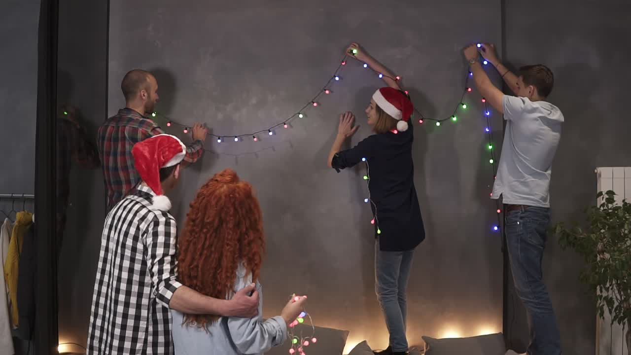 Group Of Closest Friends Decorating Room With Lights